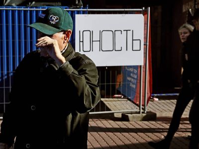 Пожилой мужчина, молодая пара и надпись "Юность" на заборе. Фото: Павел Каравашкин/Коммерсант